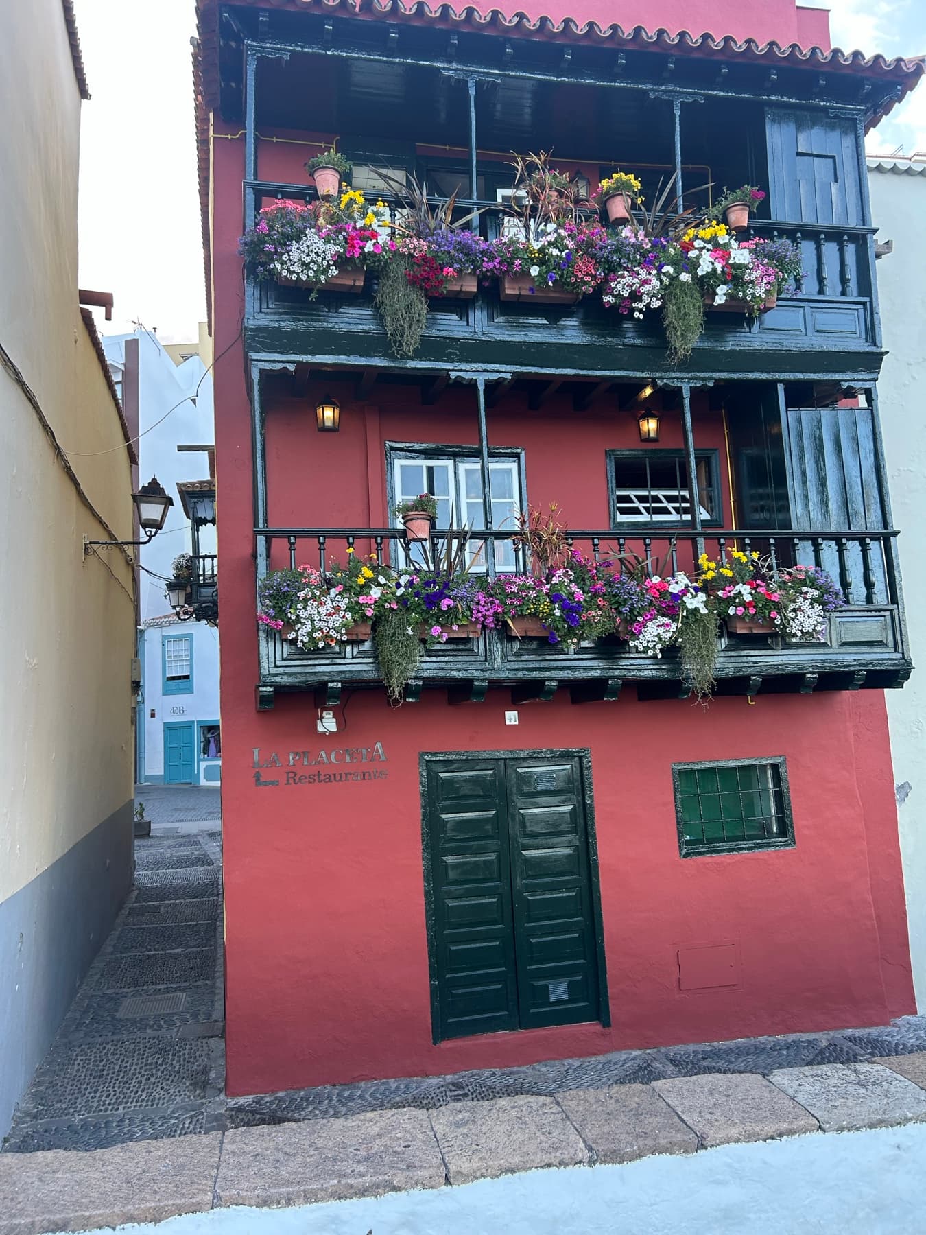 Red facade with a balcony full of flowers
