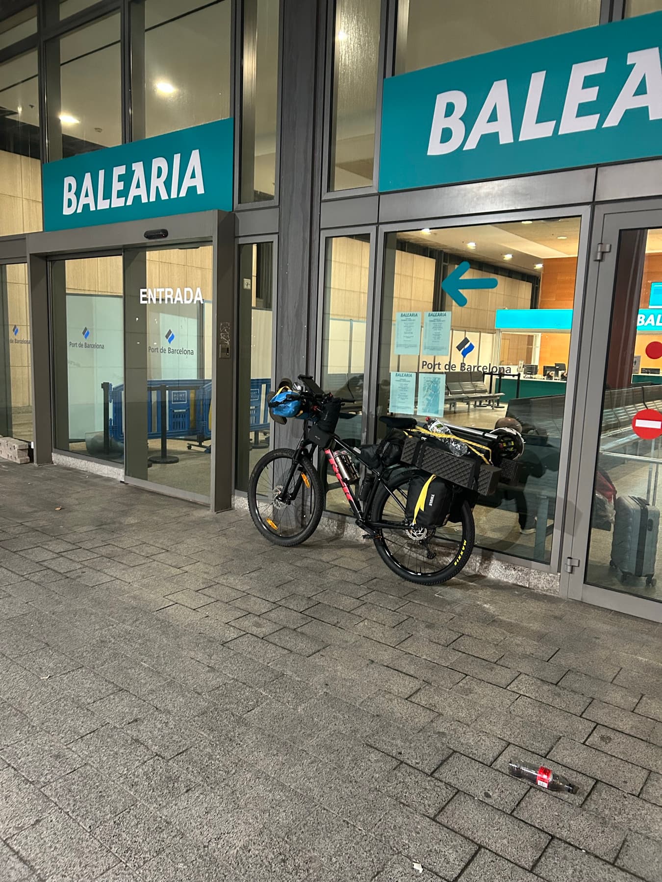 Loaded bicycle in front of the Balearia terminal at night
