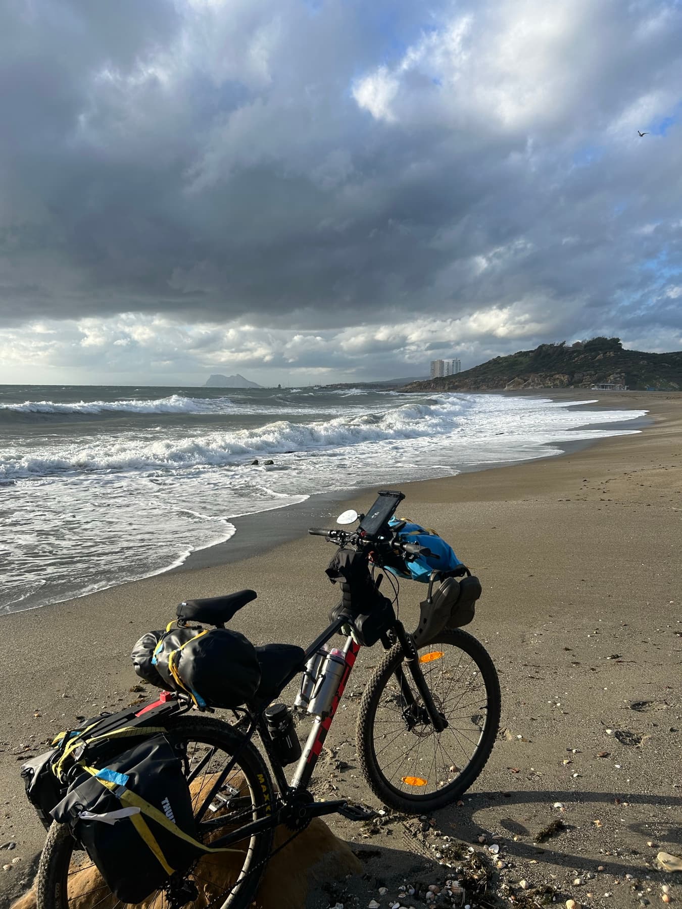 Loaded bicycle in front of a beach under stormy sky
