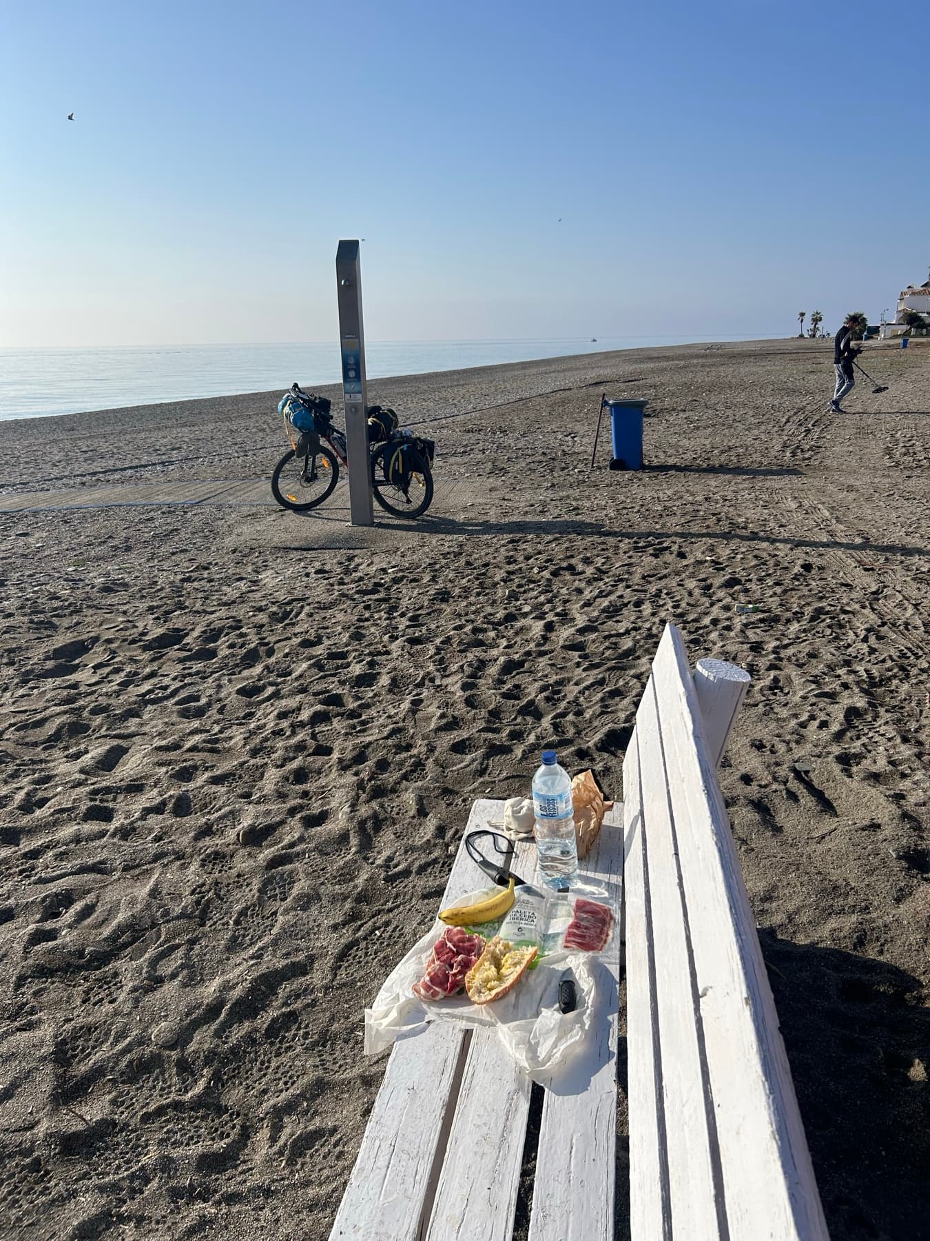 Food on a beach bench with the bicycle in the background